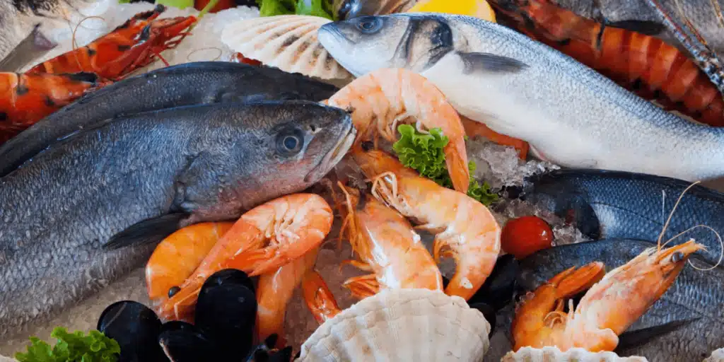 Assorted healthy seafood options suitable for diabetics, including grilled salmon, steamed shrimp, and baked cod, displayed on a well-arranged dinner table.